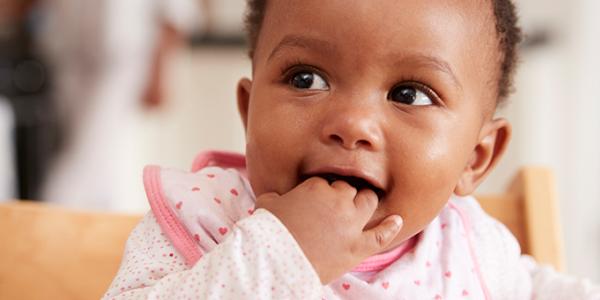 Little baby smiling with her fingers in her mouth